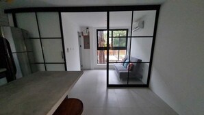 A room with a sliding door leading to a balcony, a sofa, and a dining table. - Modern 2 Bedroom Villa - 10 min. Walk to the Beach (Playa Potrero)