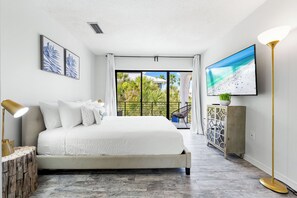 Une chambre moderne avec un grand lit, une télévision et un balcon offrant une vue agréable.