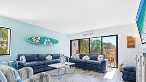 Un salon moderne avec deux canapés, une table basse et une décoration sur le thème du surf.