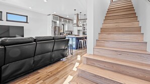 Eine moderne Küche mit weißen Schränken, einer Holztreppe und einem Ledersofa.