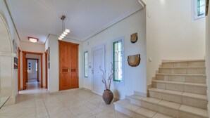 A spacious hallway with a wooden door, a vase with branches, and a staircase. - Villa MyPlaceToBe Moraira (Moraira)