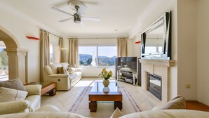 A spacious living room with a sofa, a coffee table, a TV, and a fireplace. - Villa MyPlaceToBe Moraira (Moraira)