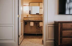 Une salle de bain d’hôtel avec un lavabo en marbre, un miroir et un meuble en bois.