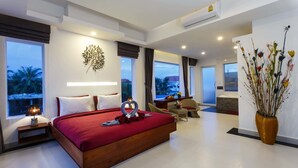 A modern hotel room with a large bed, a sitting area, and a view of palm trees. - Sleeping Angkor Hotel (Siem Reap)