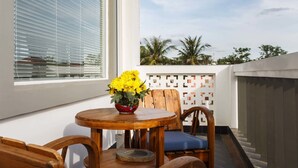 A balcony with a wooden table, a chair, and a vase of yellow flowers. - Sleeping Angkor Hotel (Siem Reap)