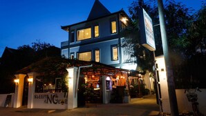 A two-story building with a sign reading "SLEEPING ANOKOR" and a covered outdoor area with seating. - Sleeping Angkor Hotel (Siem Reap)