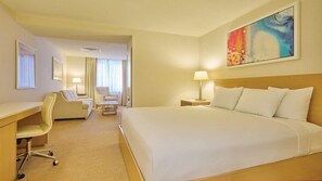 A hotel room with a large bed, a desk, a chair, and a painting on the wall. - King Room at a  Hotel (Atlantic City)