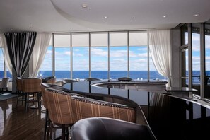 En modern inredning med en fantastisk panoramautsikt över havet, med en bardisk med sittplatser och ett stort fönster.