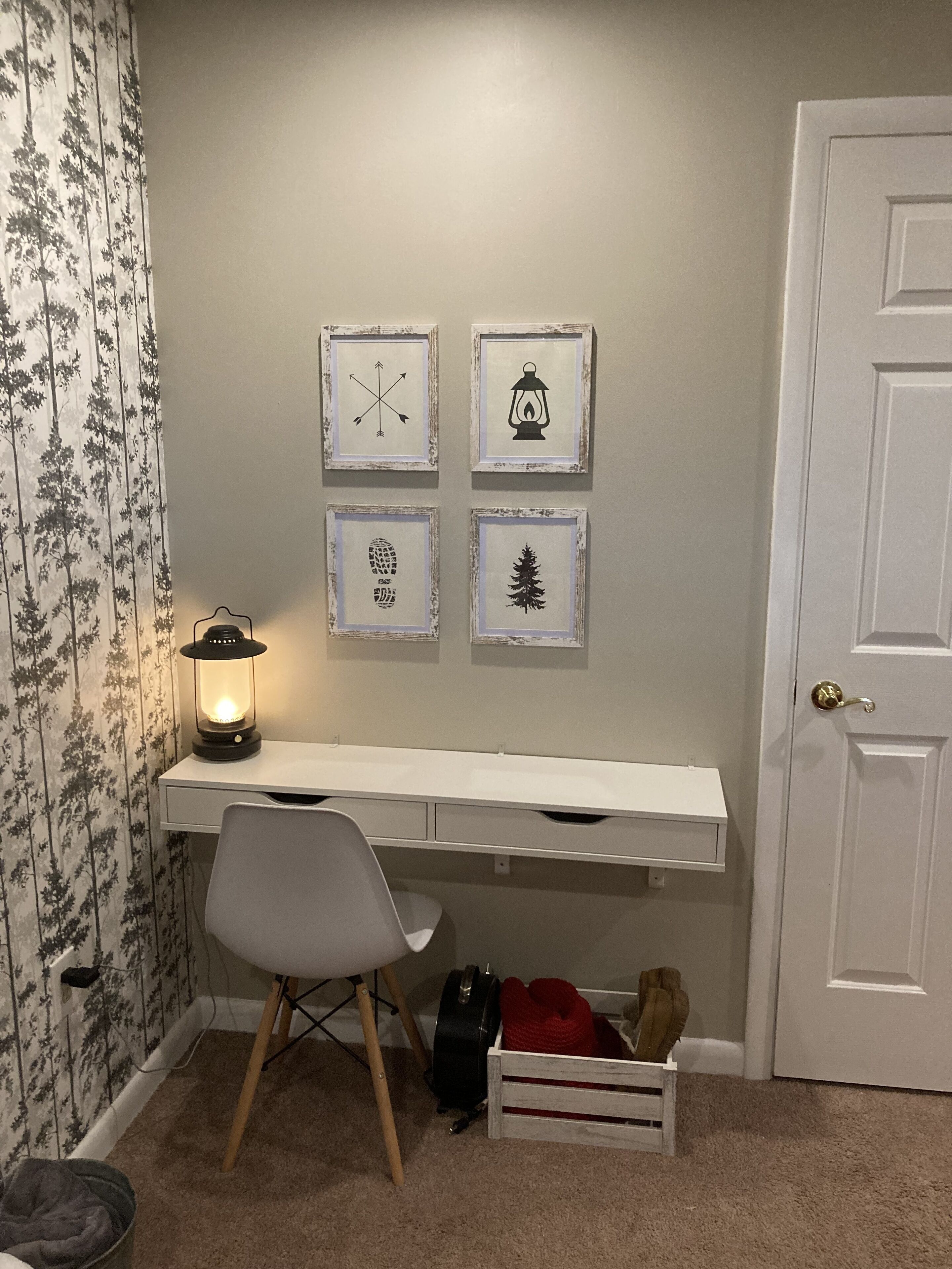 A room with a desk, chair, and four framed pictures on the wall.