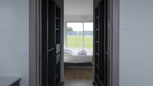 Un couloir étroit, avec un lit au fond, bordé de meubles de rangement sombres.