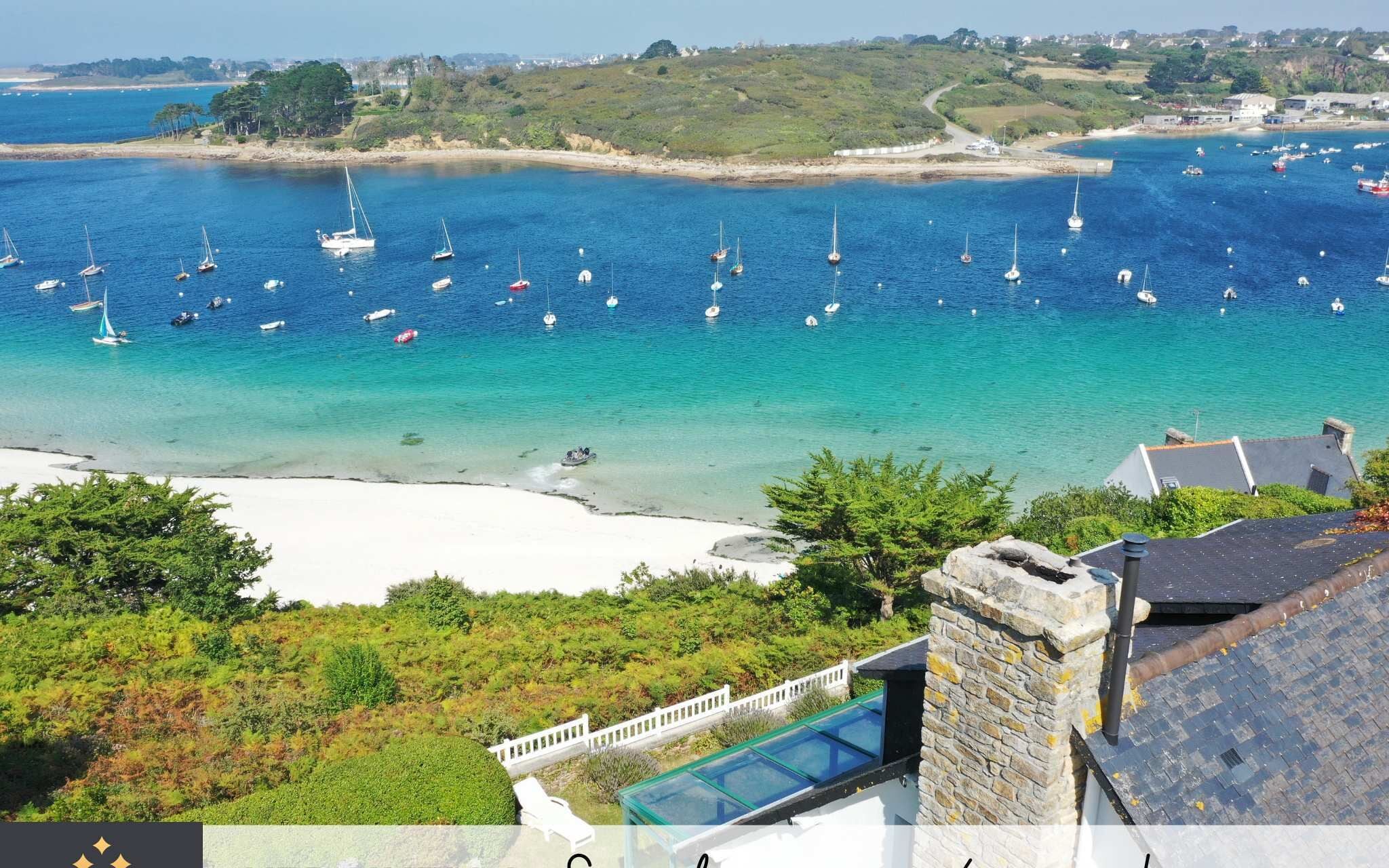 Blick auf die Küste mit Booten, einem Strand und einem Haus mit einem Steinkamin.