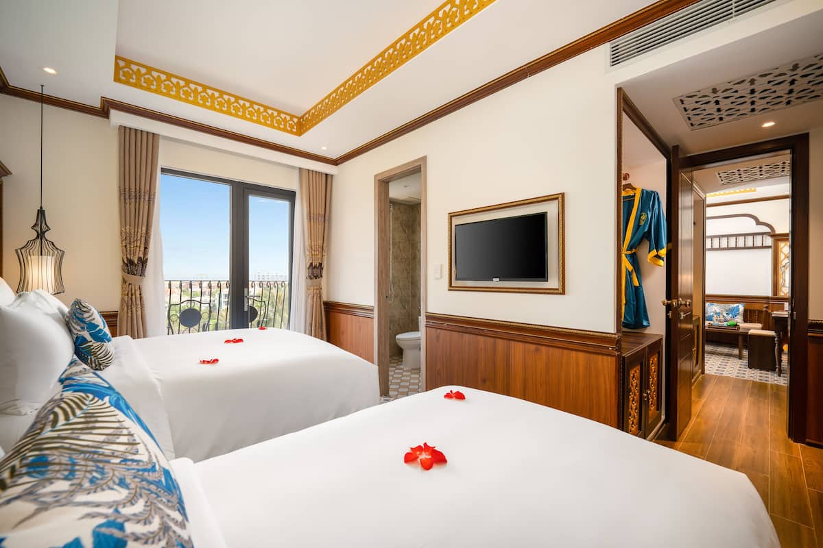 A hotel room with two beds, a TV, and a balcony with a view.
