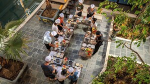 A rooftop dining area with multiple tables and chairs, surrounded by potted plants and a pool. - Soleil by Soluna - A Charming Touch of Hoi An's Heritage (Da Nang)