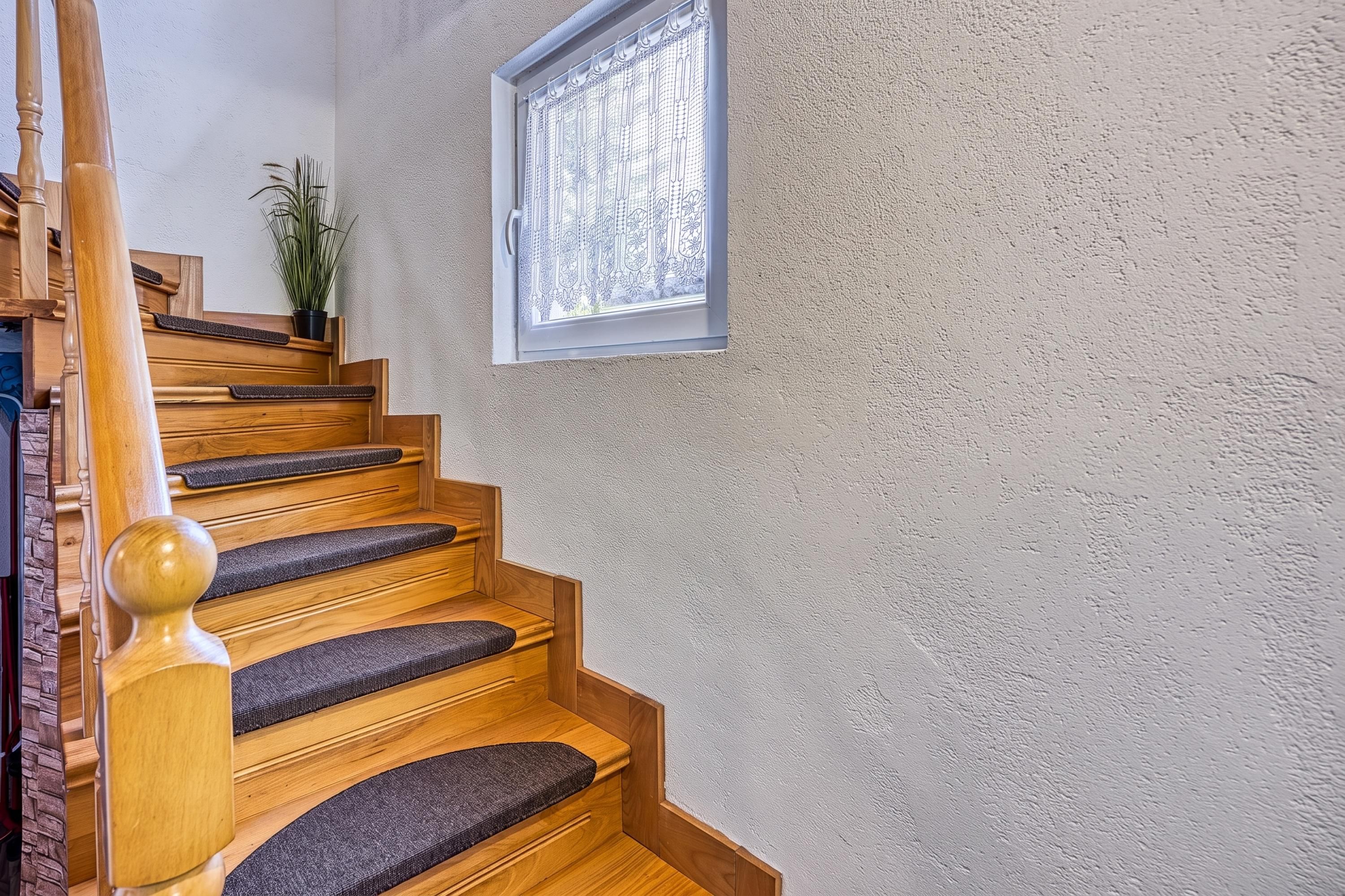 A wooden staircase with a handrail and carpeted steps leading to a landing.