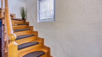 A wooden staircase with a handrail and carpeted steps leading to a landing.