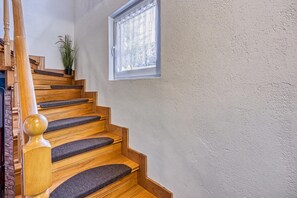 Eine Holztreppe mit Handlauf und Teppichstufen, die zu einer Zwischenebene führt.
