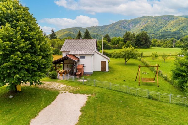 A house with a fenced yard, a swing set, and a path leading to the house.