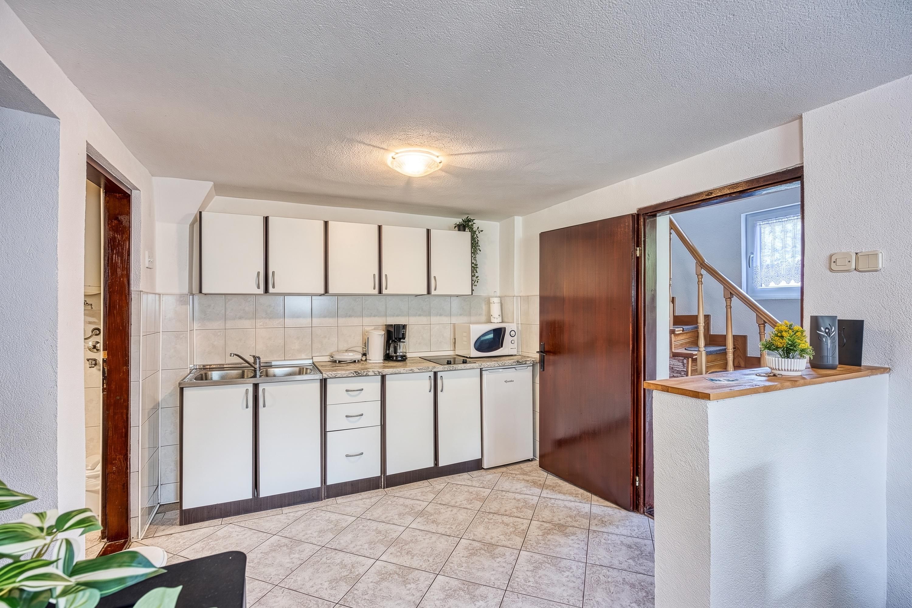 A compact kitchen with white cabinets, a built-in microwave, and a coffee maker.