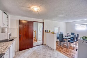 A modern kitchen with a built-in microwave, a wooden door, and a dining area with a table set for four.