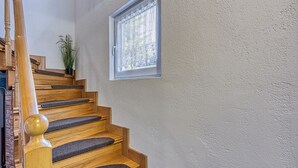 A wooden staircase with dark carpeted steps and a wooden handrail.