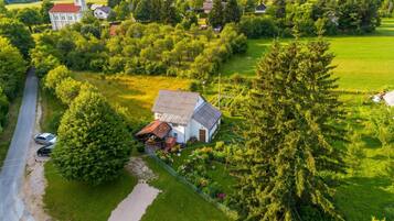 Luchtbeeld van een landelijk gebied met een wit huis, een kerk en een grote boom.