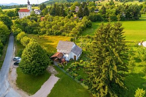 Luchtbeeld van een landelijk gebied met een wit huis, een kerk en een grote boom.