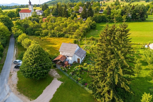 An aerial view of a rural area with a white house, a church, and a large tree.