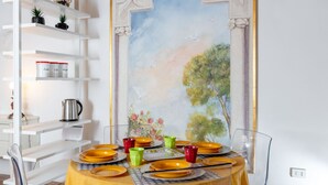 A dining area with a table set for four, surrounded by white shelves with various items.