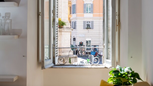A window with a view of a street, buildings, and a bicycle.