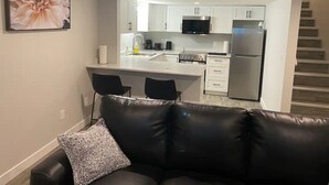 A modern kitchen with white cabinets, stainless steel appliances, and a black microwave.