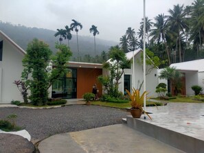 A modern building with a large glass entrance, surrounded by tropical vegetation and palm trees.