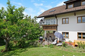 Ein zweistöckiges Haus mit Balkon, Grillplatz und Terrasse mit Gartenmöbeln.