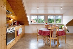 Eine Küche mit Holzausstattung, einem Herd und einem Essbereich mit Tisch und Stühlen.