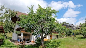 Et boligområde med et hus, der har en balkon, et spiseområde med udendørs møbler og en velplejet græsplæne.
