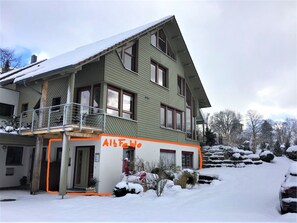 Ein zweistöckiges Gebäude mit Balkon und einem Schild mit der Aufschrift 'Alte FwO', umgeben von Schnee.