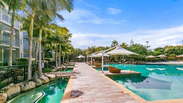 Ein Poolbereich eines Resorts mit Holzterrasse, Liegestühlen und Sonnenschirmen.