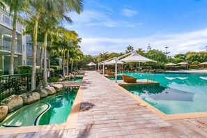 Ein Poolbereich eines Resorts mit Holzterrasse, Liegestühlen und Sonnenschirmen.