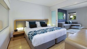 Ein modernes Schlafzimmer mit einem großen Bett, Nachttischen, einer Couch und Blick ins Freie.