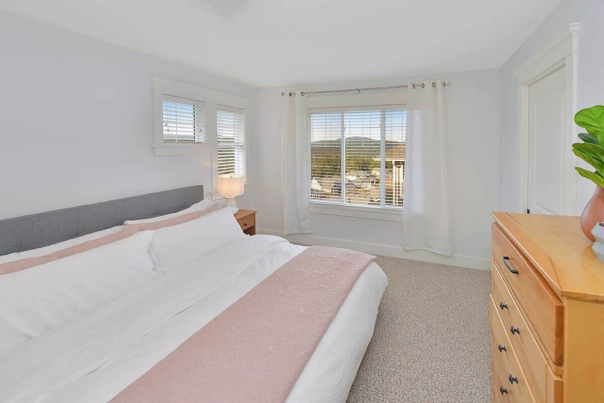 A bedroom with a bed, a dresser, a nightstand, and a window with blinds.