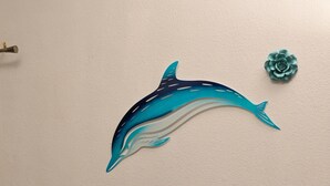 A wall with a dolphin decal, a small table with a basket, candles, and a stack of wooden blocks.