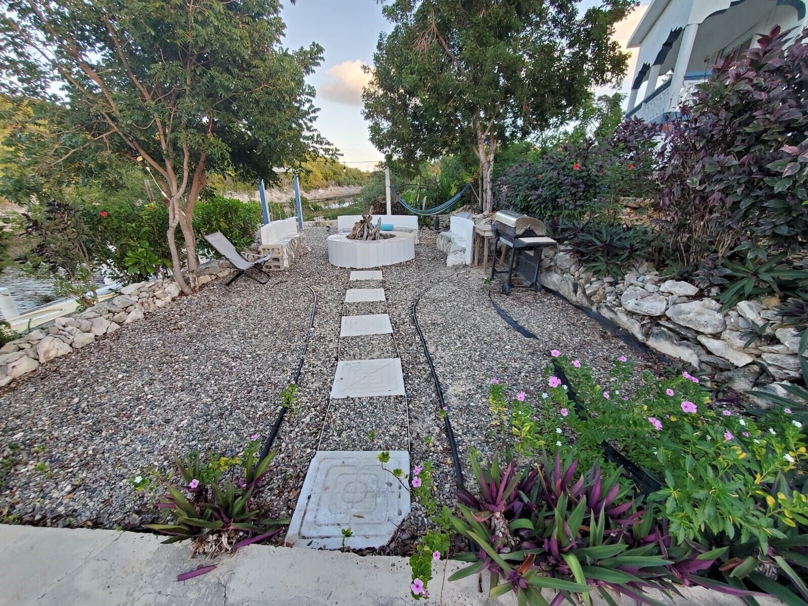 Un patio jardín con un sendero de piedra, zona de estar y una chimenea.