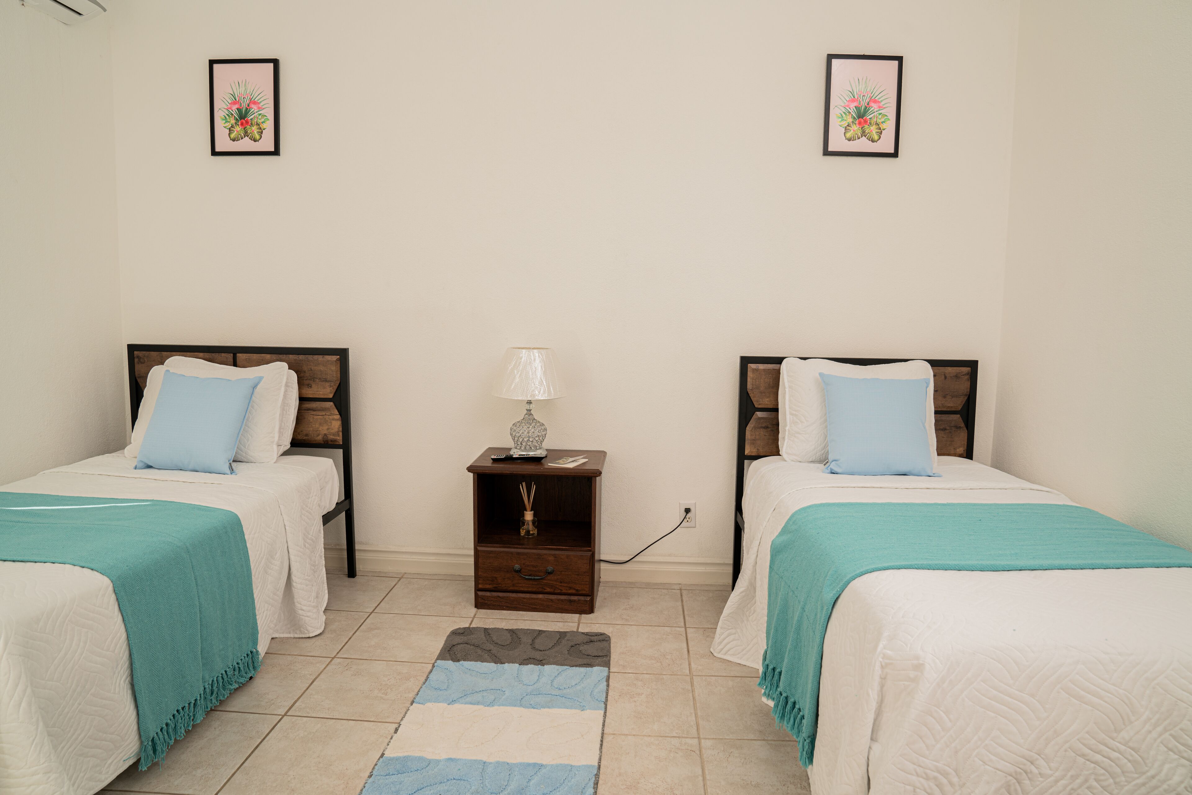 A twin room with two beds, a nightstand, a lamp, and a rug.