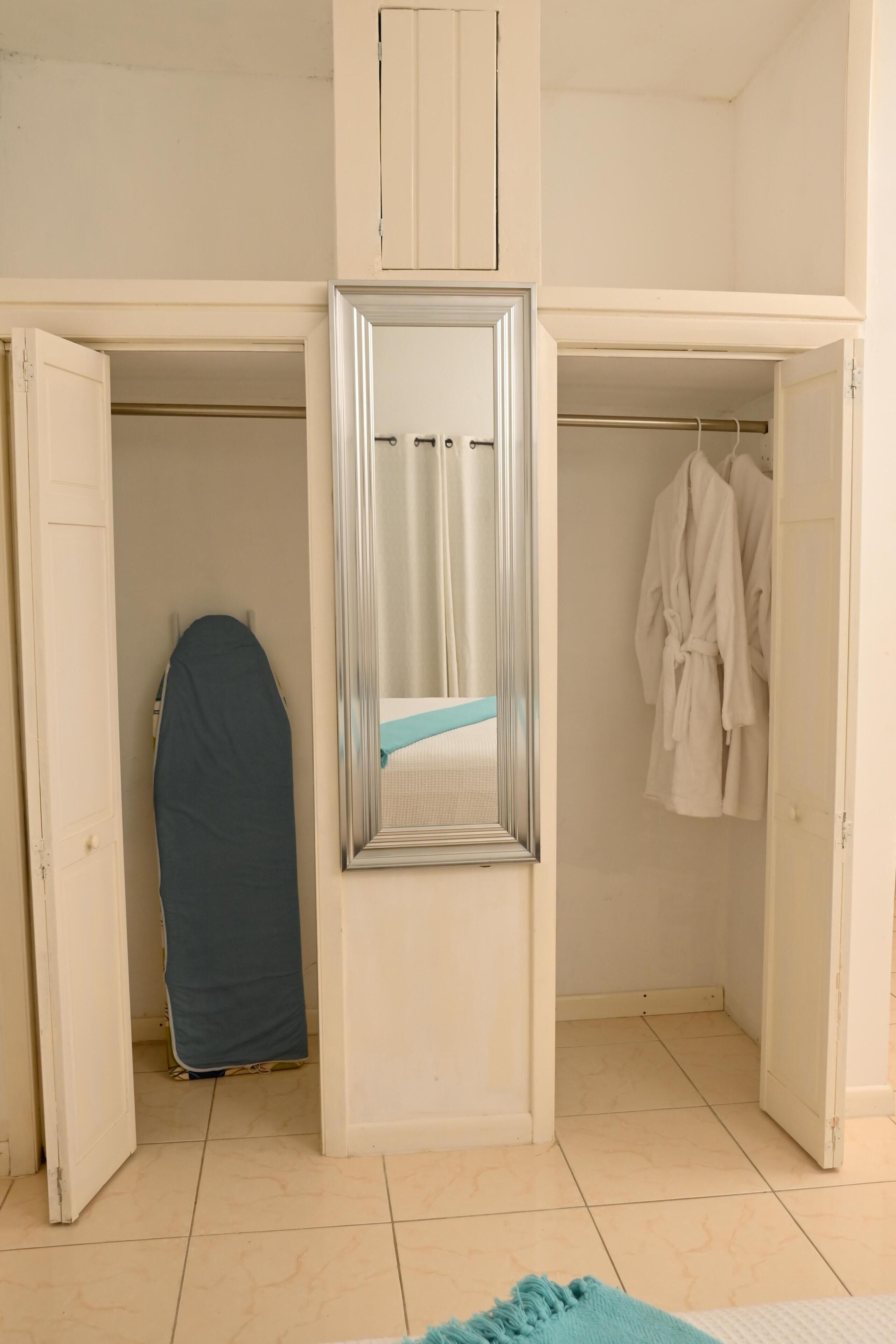 Una habitació amb un armari, un mirall i una gàbia per a roba penjada.