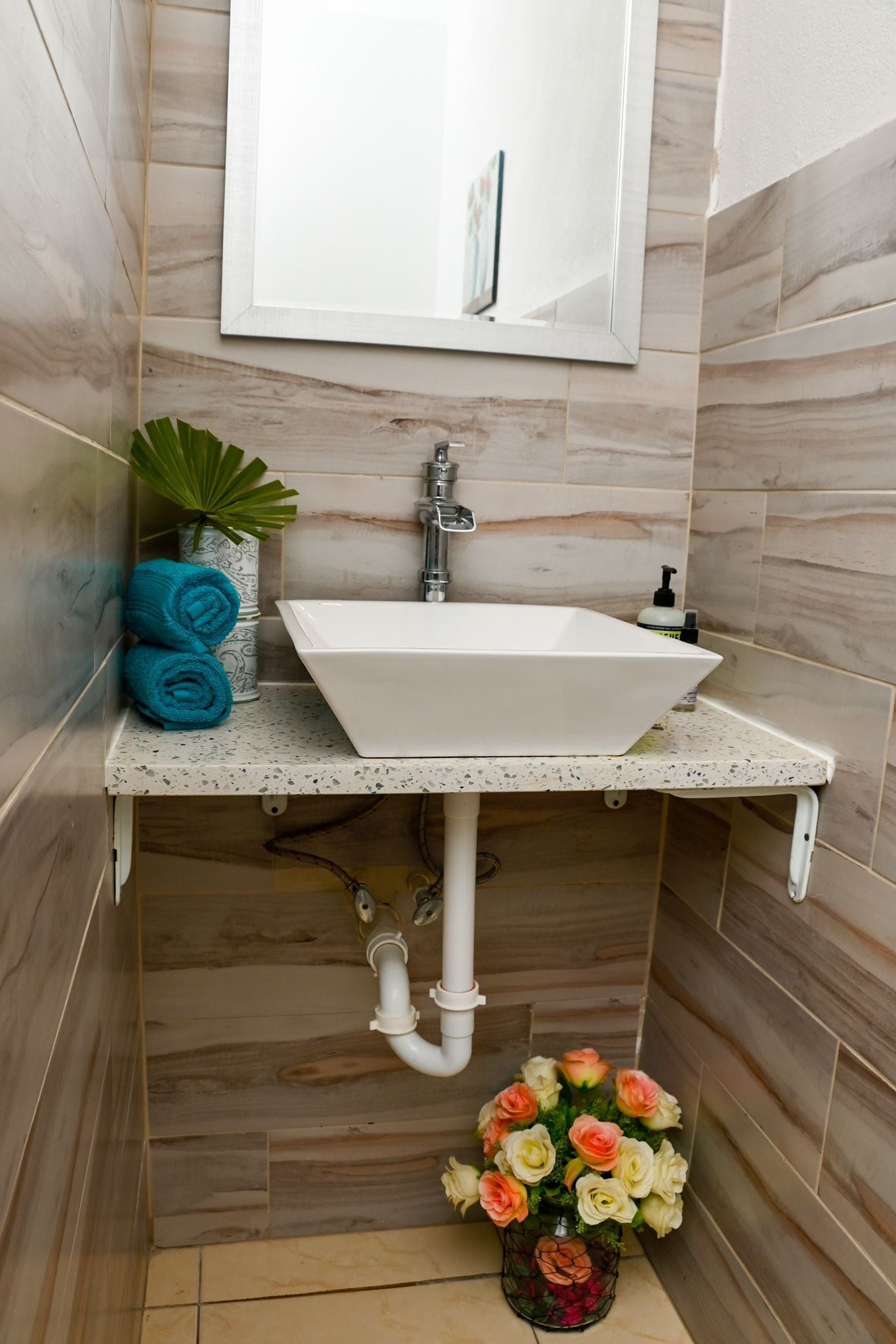 Un baño con un lavabo blanco, un espejo y una planta en maceta.