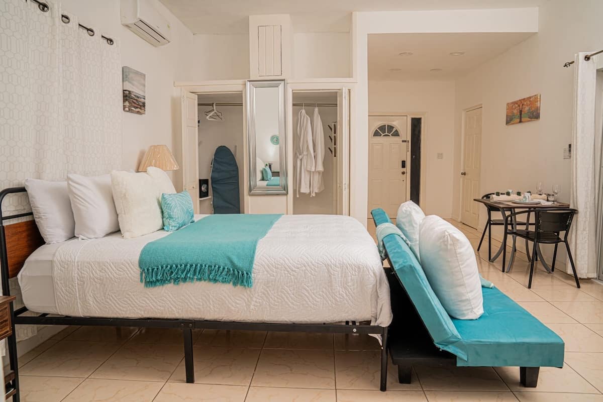 A bedroom with a bed, a bench, a table with chairs, and a closet.