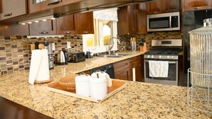 A kitchen with granite countertops, stainless steel appliances, and wooden cabinets.