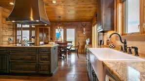 Una cocina con armarios de madera, una isla grande con un lavamanos y una zona de comedor con sillas.