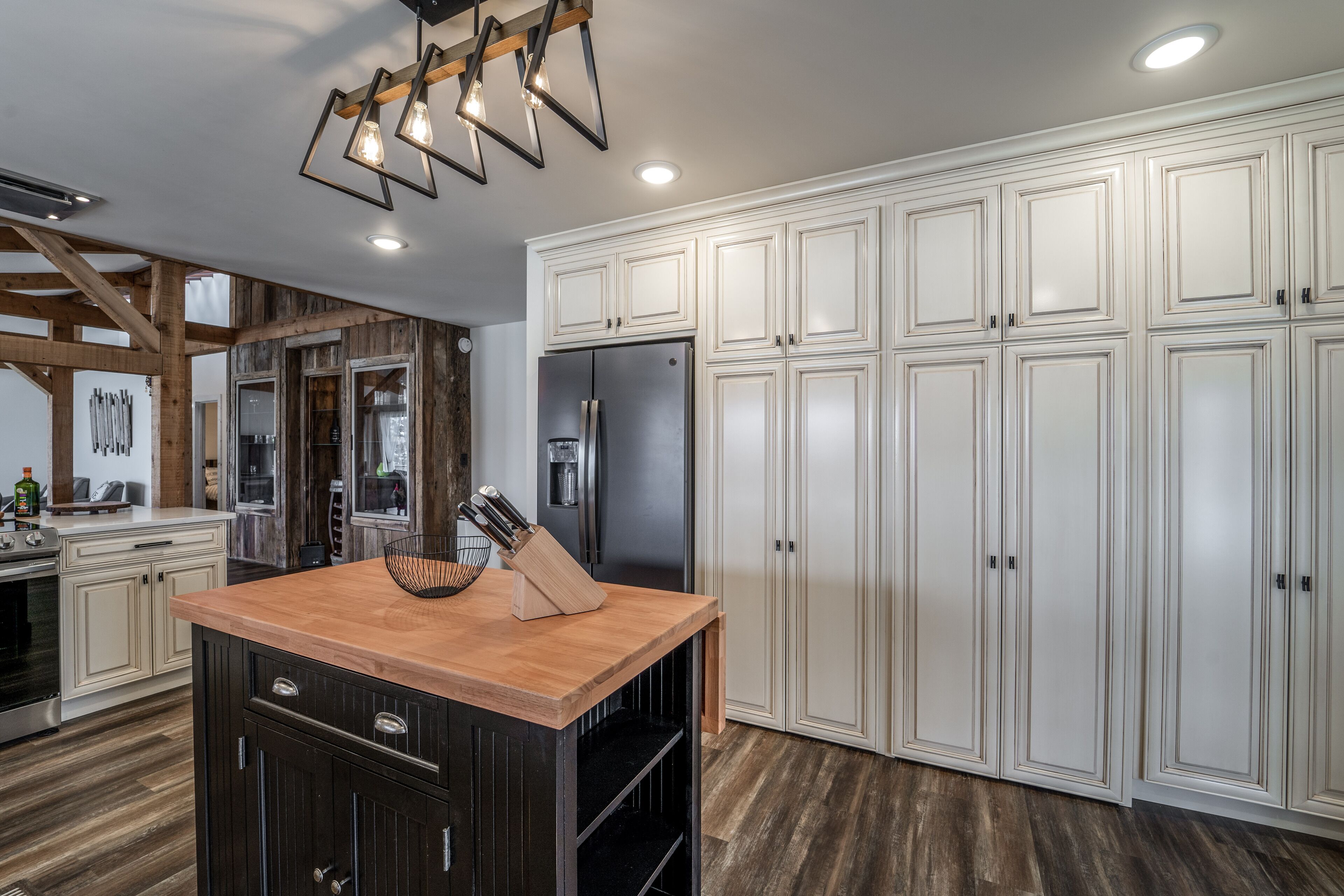 A modern kitchen with white cabinetry, a central island, and a stainless steel refrigerator.