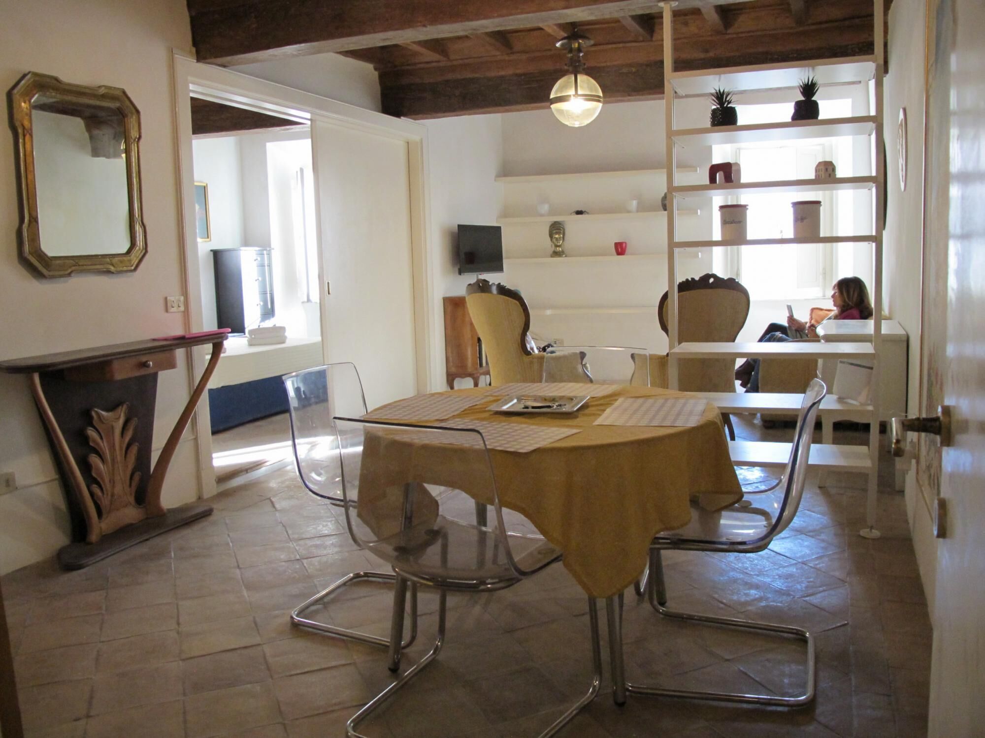 A dining area with a round table, chairs, a chandelier, and a bookshelf.