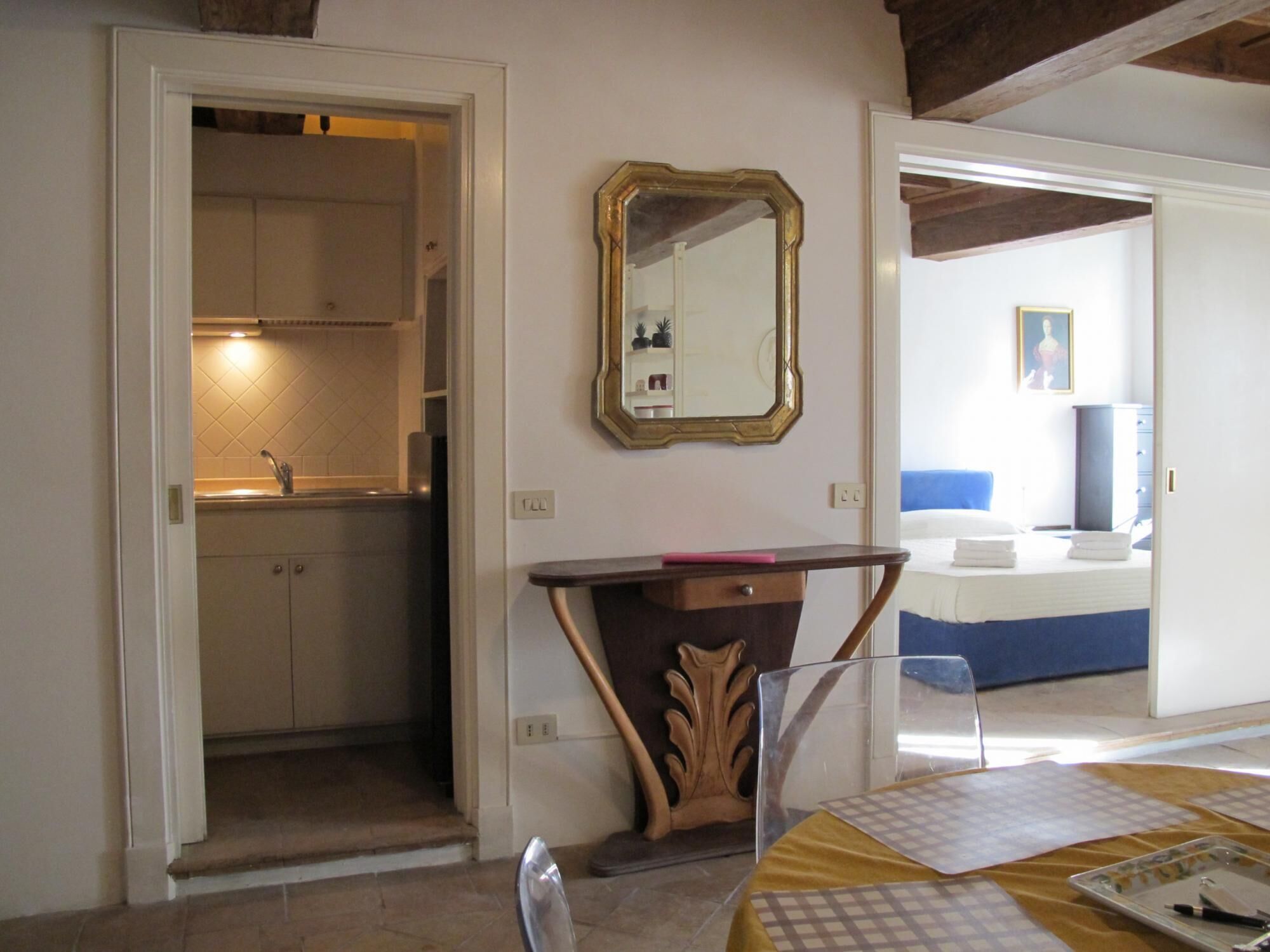 Ein Hotelzimmer mit Bett, Nachttisch, Spiegel und Blick ins Bad.